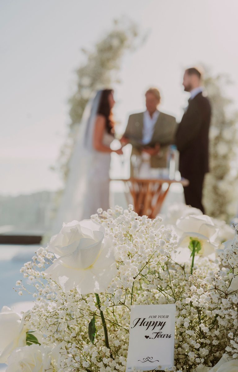 Wedding ceremony flowers and couple exchanging vows at Royal Myconian, Mykonos