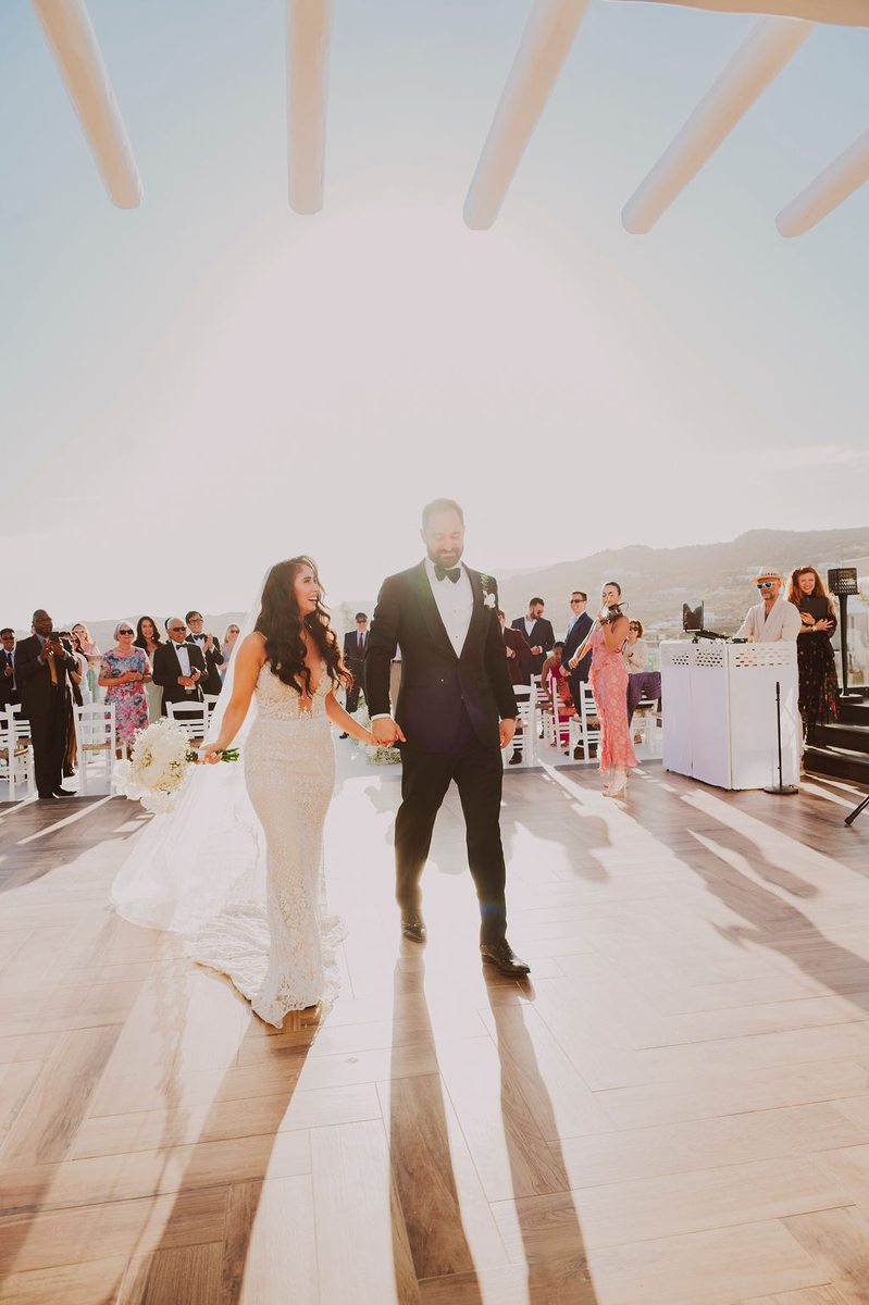 Bride and groom recessional at Royal Myconian, Mykonos – DJ Seitan setup visible