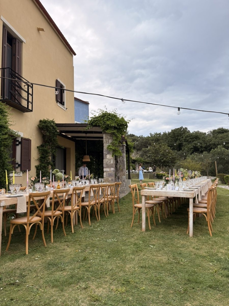 Outdoor wedding dinner tables set up at Chara Houses, Mani, with string lights and colourful candles