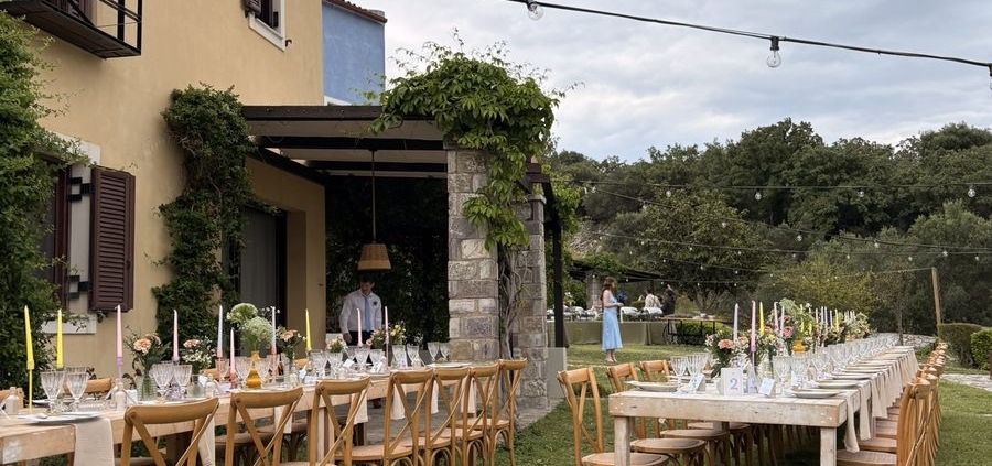 Outdoor wedding dinner tables set up at Chara Houses, Mani, with string lights and colourful candles