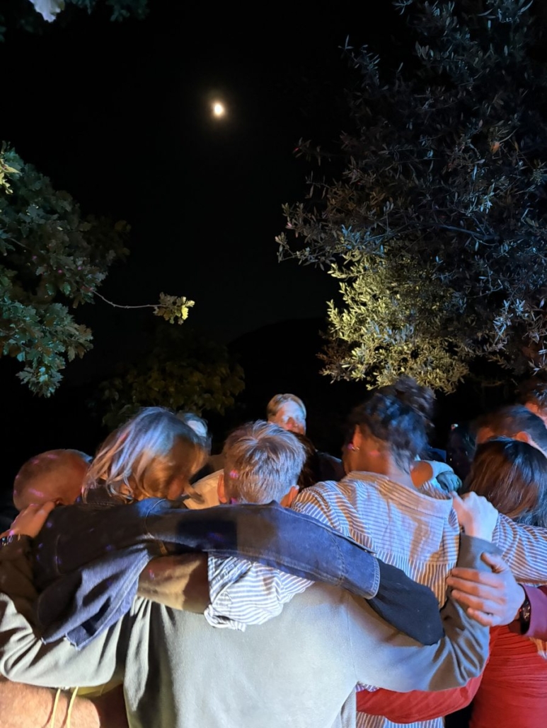 Wedding guests dancing together under the moonlight at Chara Houses, Mani
